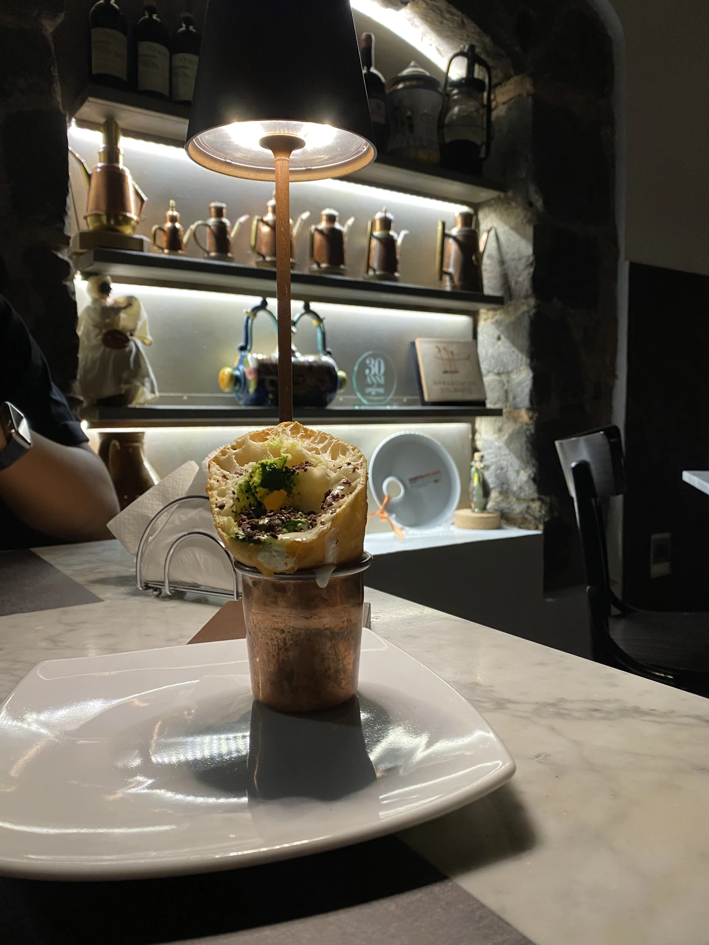Cono pizza fritta Ciro servito in bicchiere di rame sotto la calda luce della lampada da tavolo custom a Pepe in Grani
