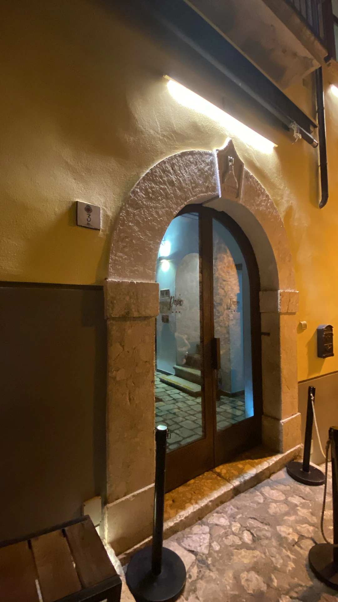 Portale in pietra calcarea scolpita con illuminazione LED radente a luce calda all'ingresso di Pepe in Grani a Caiazzo